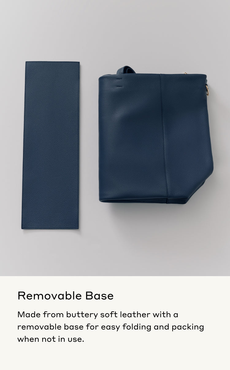 Flat rectangular base beside upright handbag with handle and zipper closure.