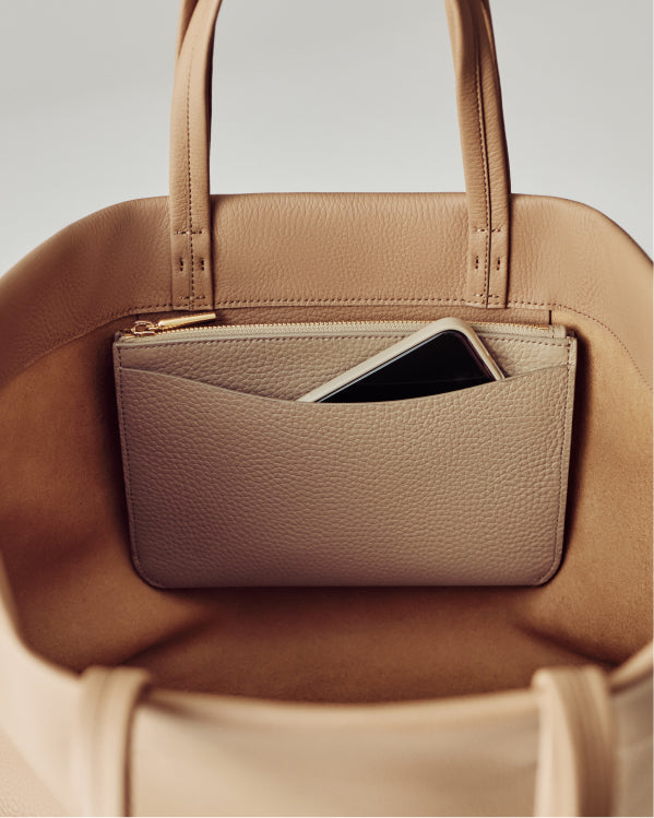 Open handbag showing interior pocket with a smartphone inside.