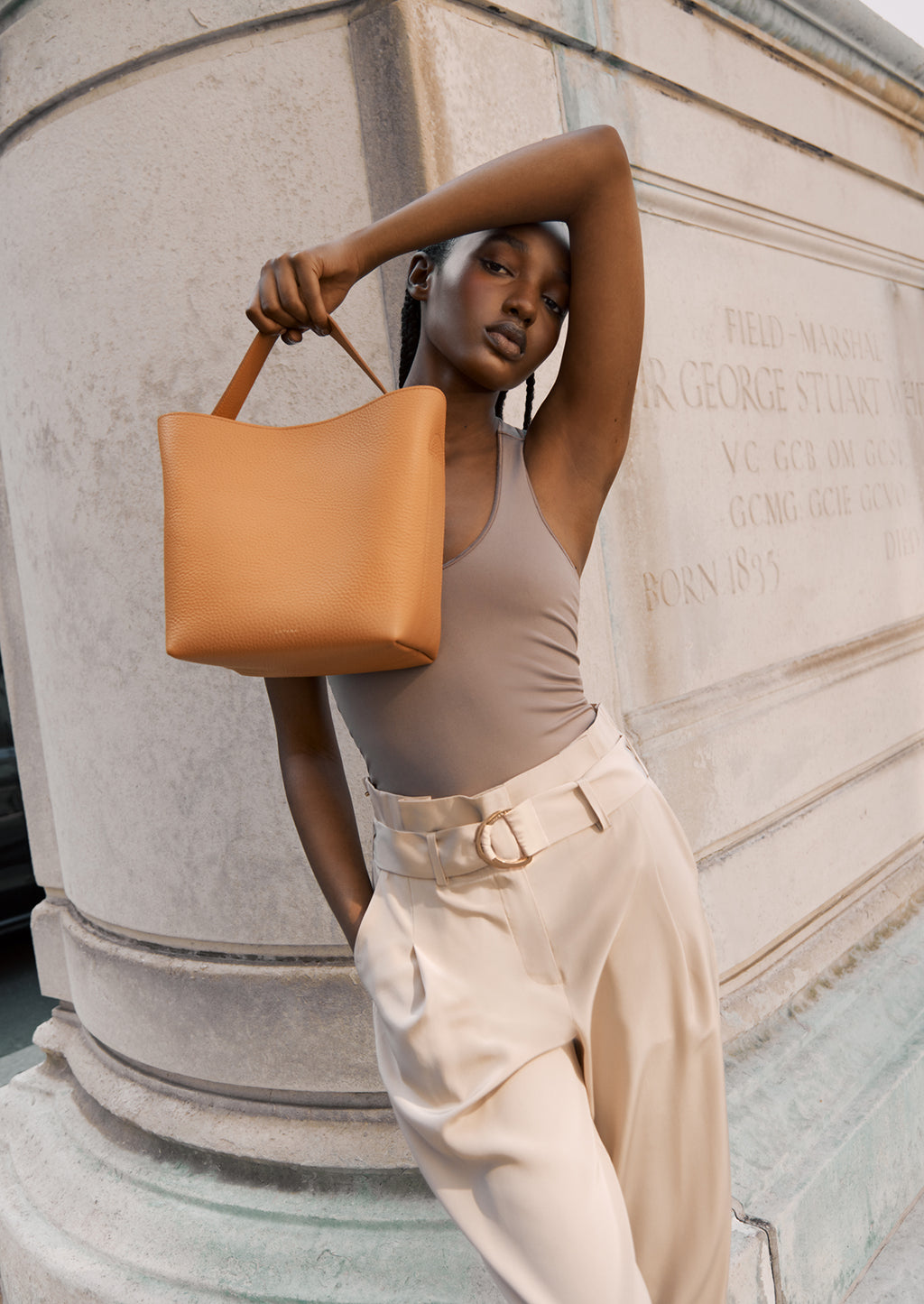 Woman posing with a bag next to a historical marker.