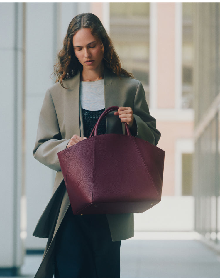 Person standing with a large handbag outside a building.