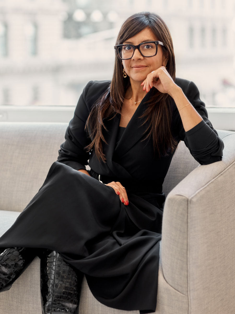 Woman sitting on a sofa wearing glasses and croc-embossed leather boots