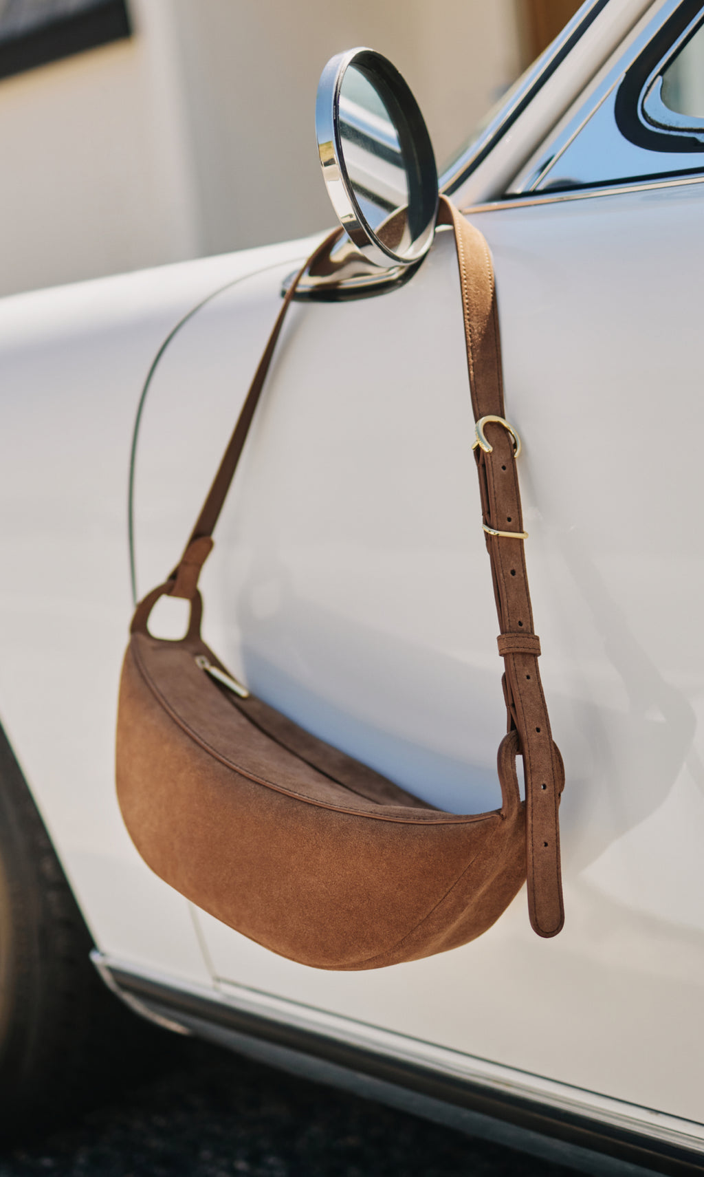 Bag hangs on car mirror handle outdoors.