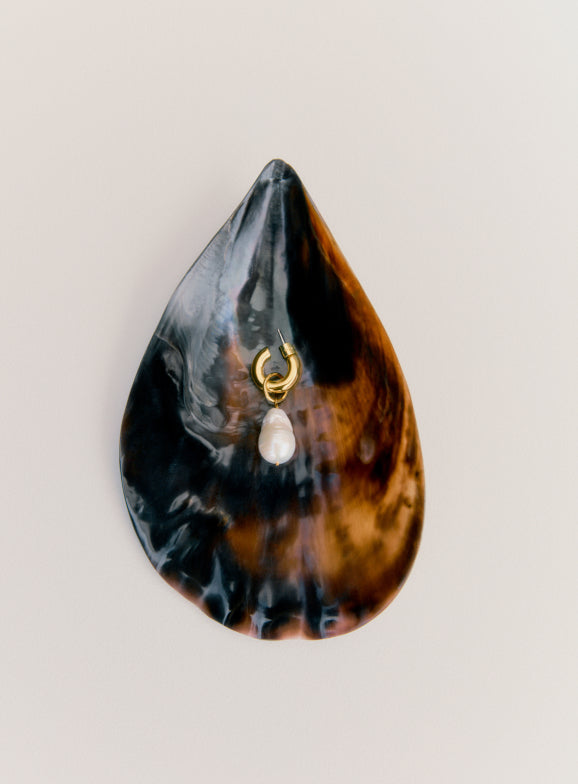 Shell-shaped object with a hanging pendant attached.