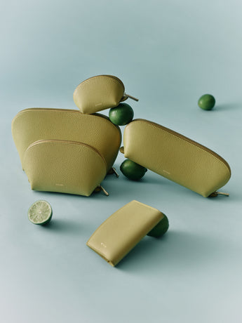 Assorted pouches and a wallet displayed with whole and halved limes nearby.