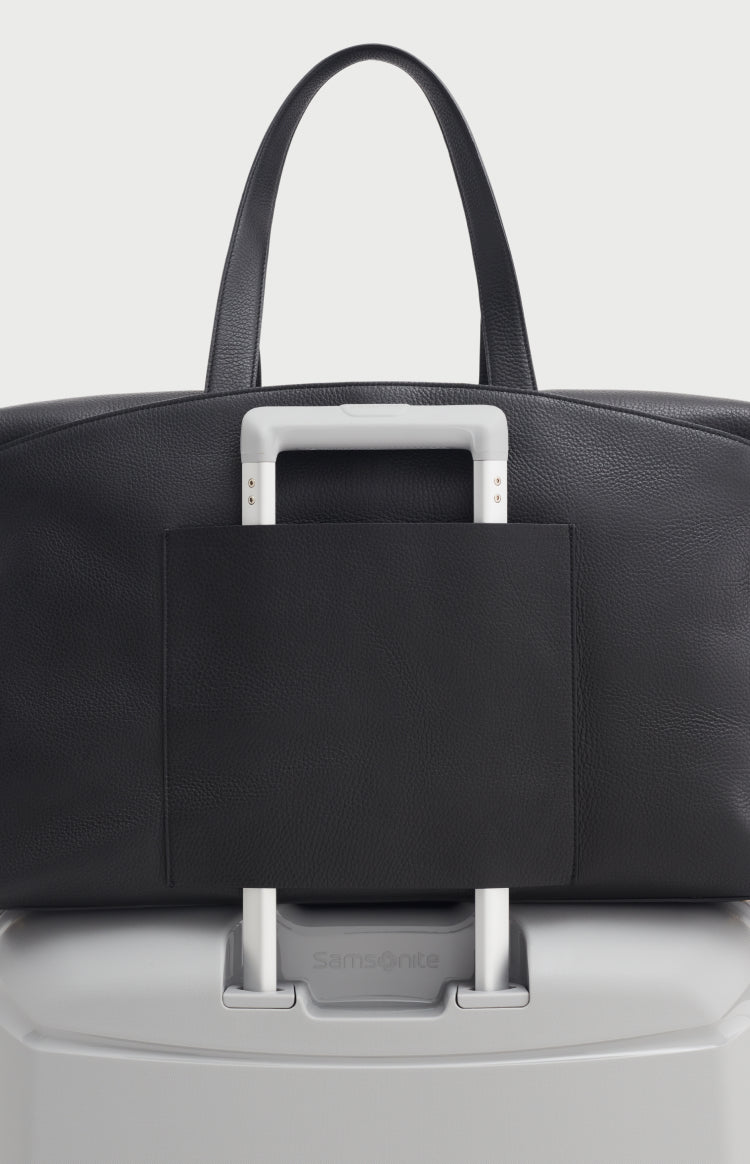 A handbag placed on top of a suitcase handle