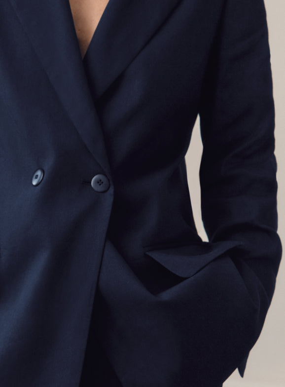 Person in a suit with one hand in pocket.