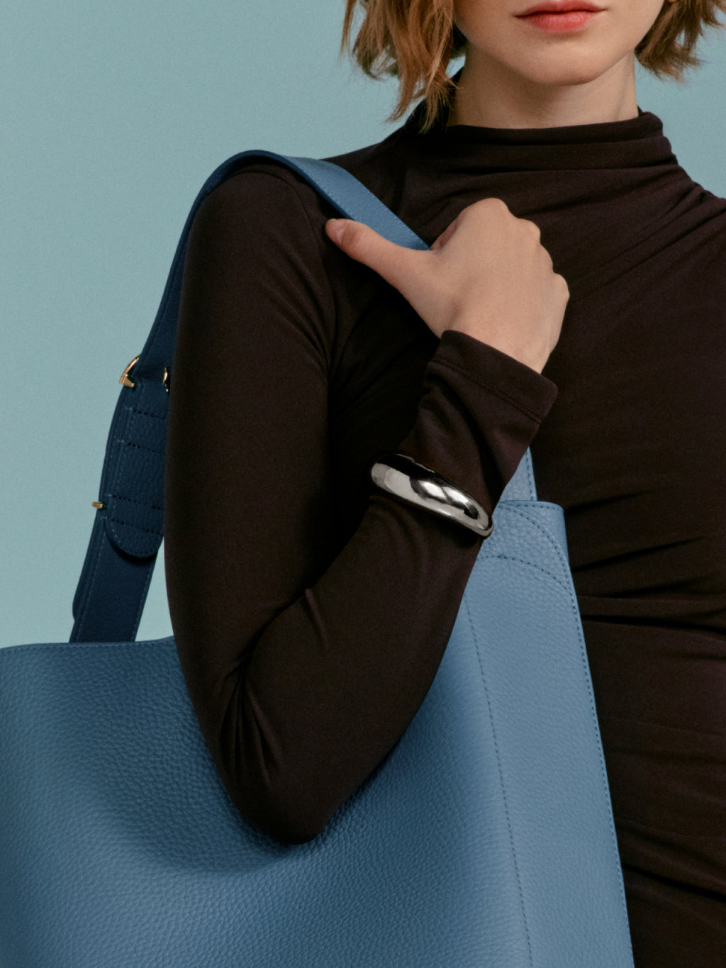 Person carrying a shoulder bag, pointing with finger