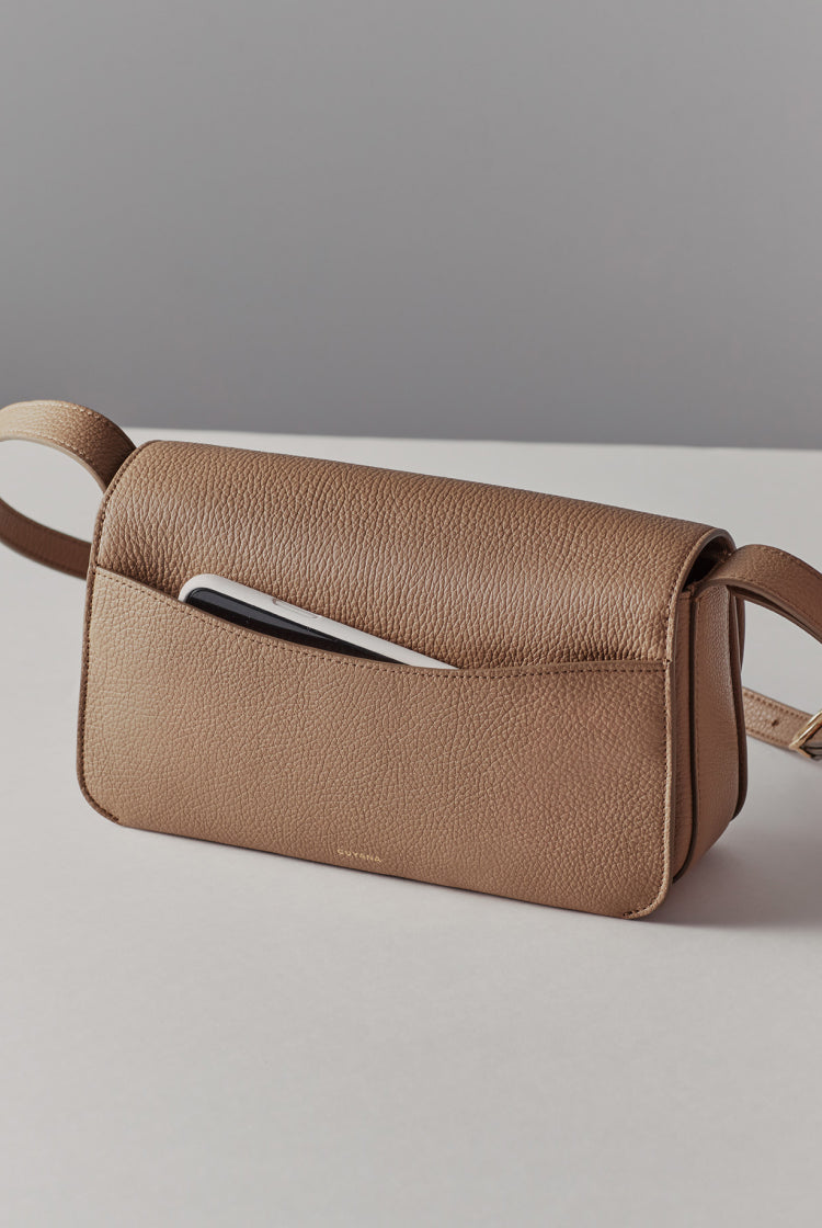 Small bag with a front flap and shoulder strap, with a pen in front pocket.