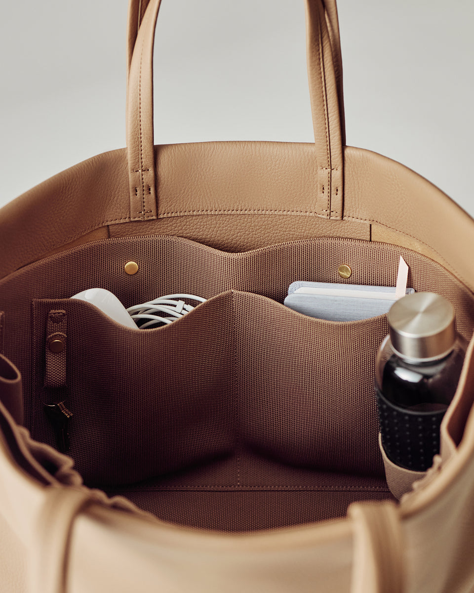 Open tote bag with items like a bottle and notebook inside.