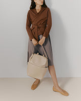 Person wearing a wrap top and skirt holds a large backpack