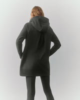 Person wearing hooded sweater and pants, facing away.