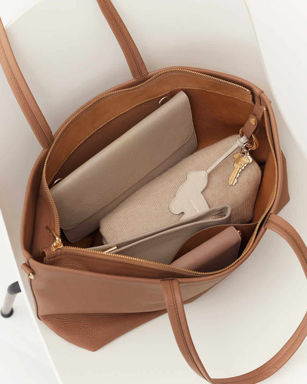 Open tote bag with a wallet, pouch, and keys inside.