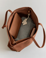 Open tote bag with a wallet, scarf, and keychain inside.