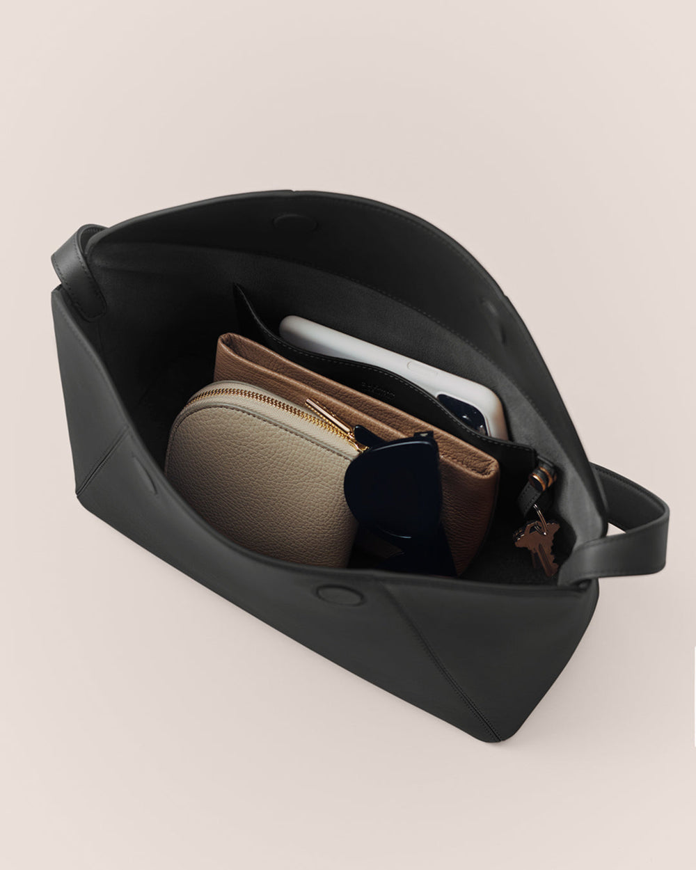 Open travel bag with pouches, sunglasses, and a phone inside.
