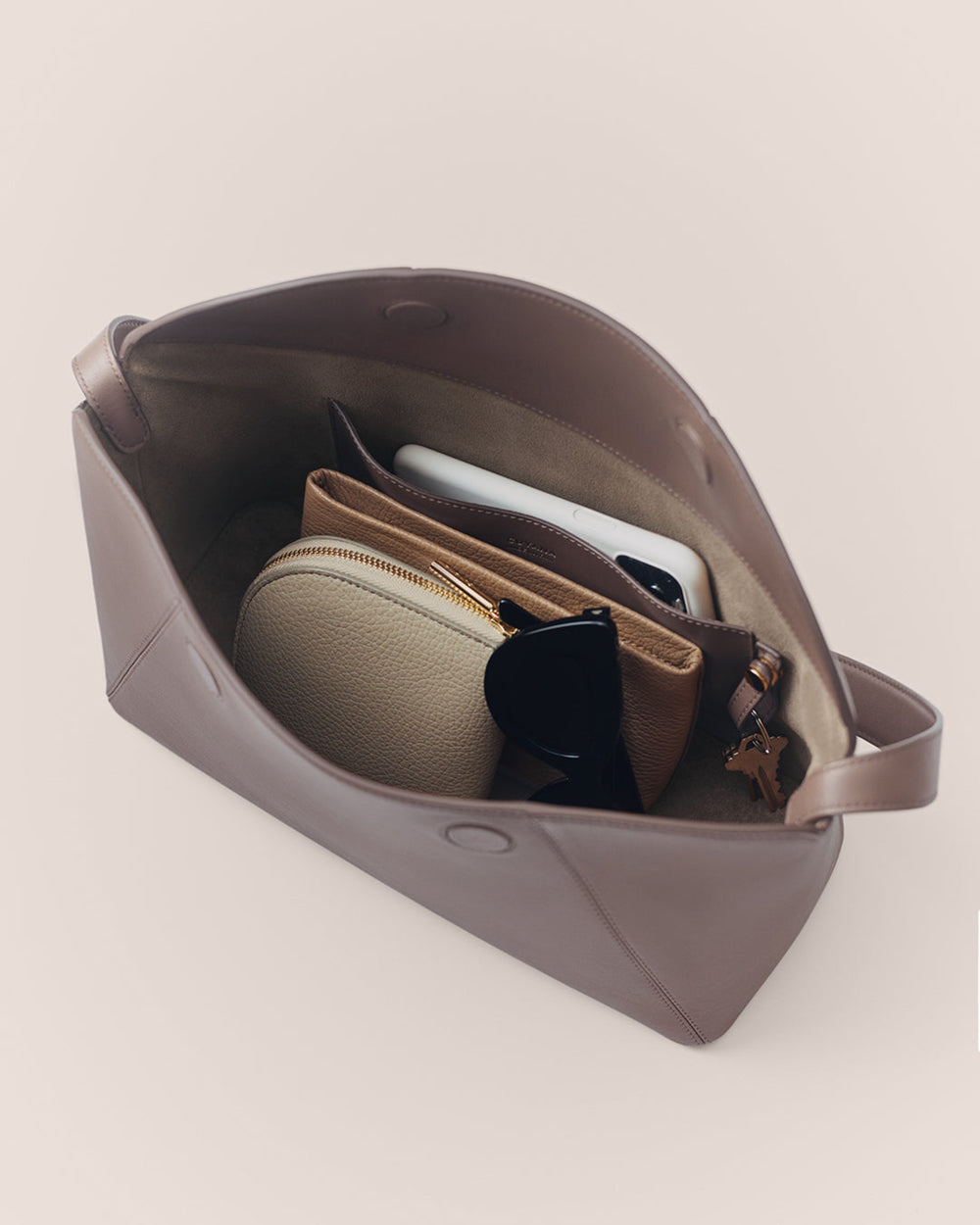 Open handbag with pouches, sunglasses, and a phone inside