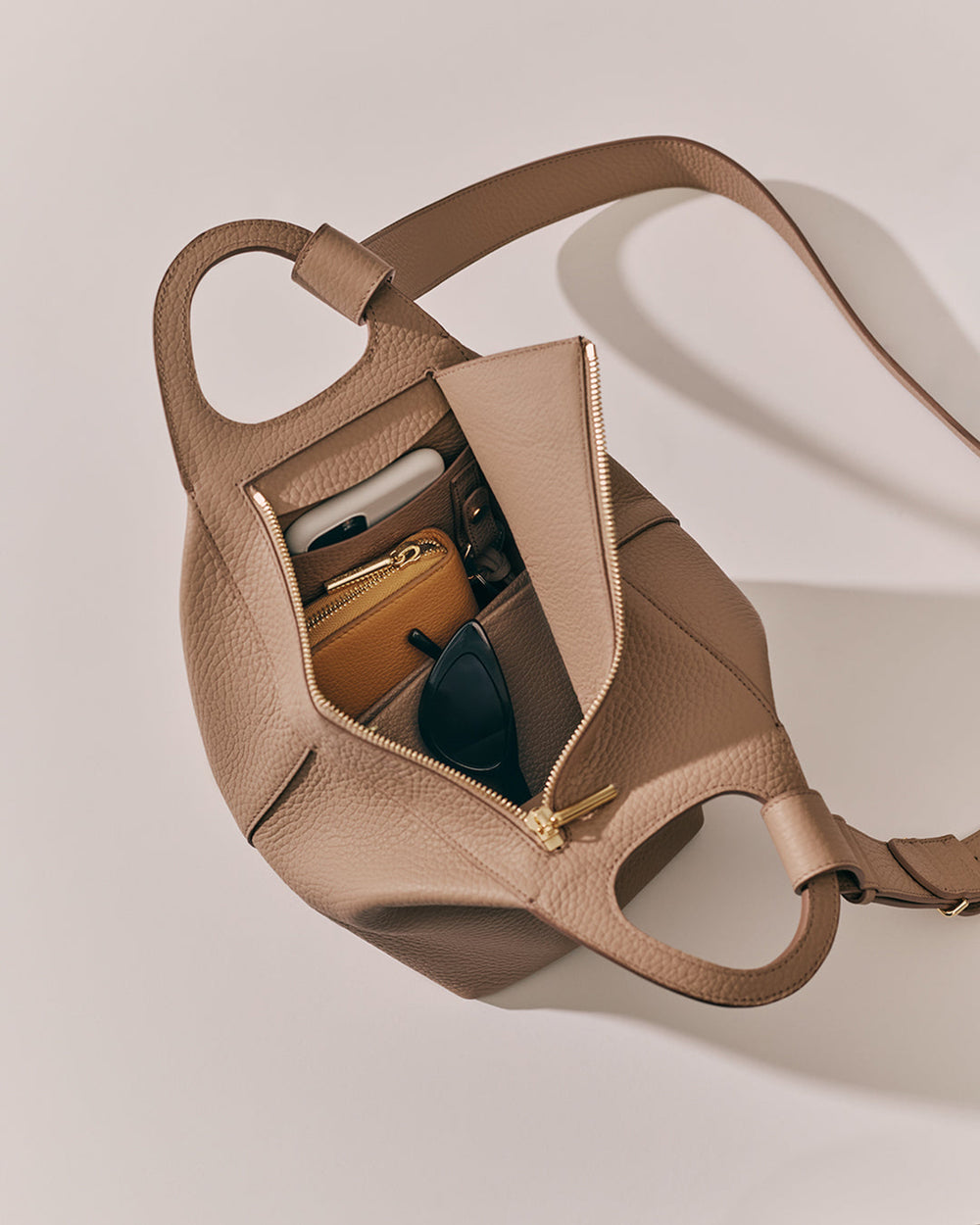 Open travel bag with items like sunglasses and a wallet inside.