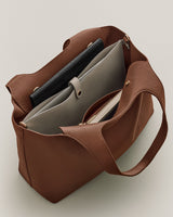 Open handbag with various items inside, including a tablet and a zippered pouch.
