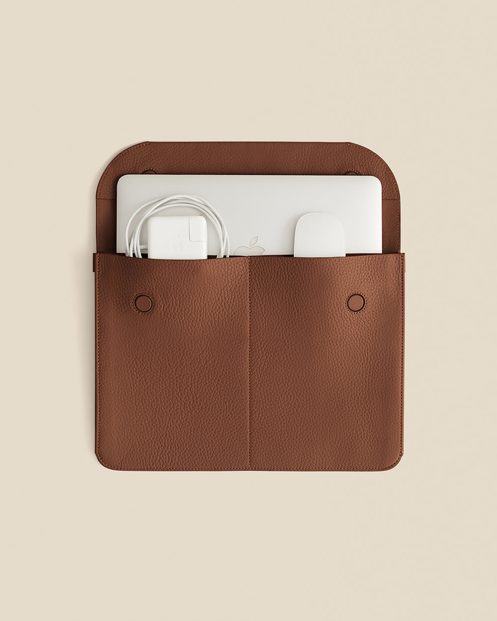 Leather case with laptop and charger inside, viewed from above.
