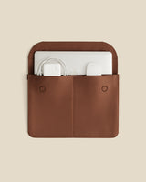 Leather case with laptop and charger inside, viewed from above.