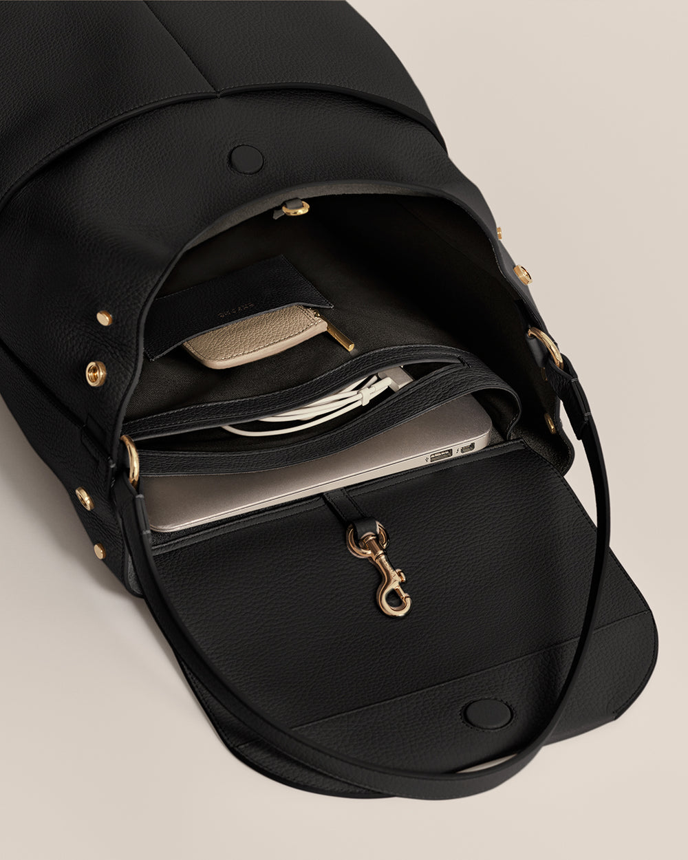 Open backpack showing contents like a laptop, wallet, and a hanging key clip.