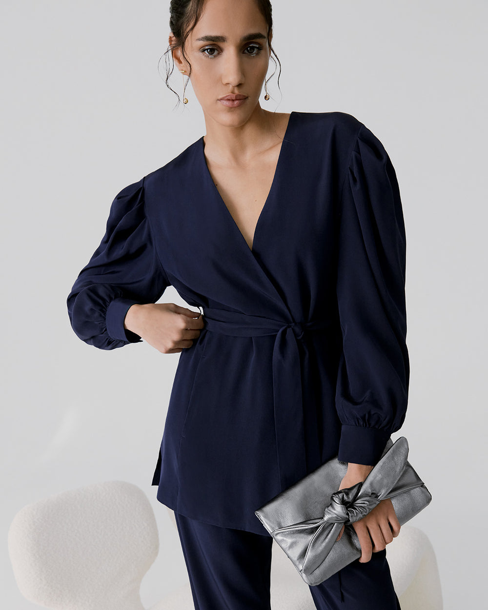 Woman posing with hand on hip holding a clutch bag
