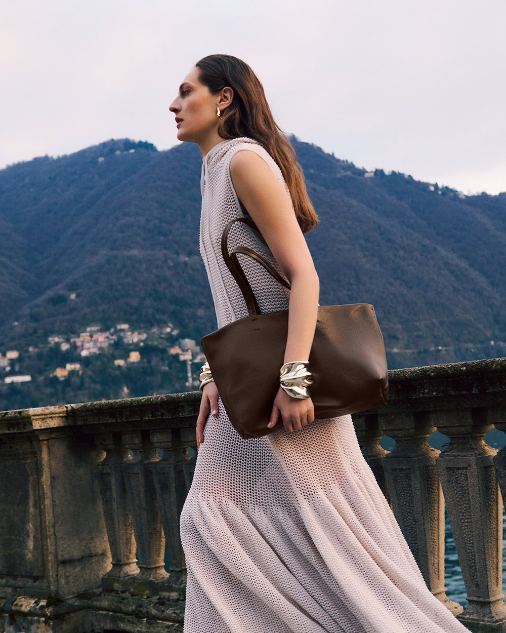 Woman with handbag standing on terrace, mountains in background
