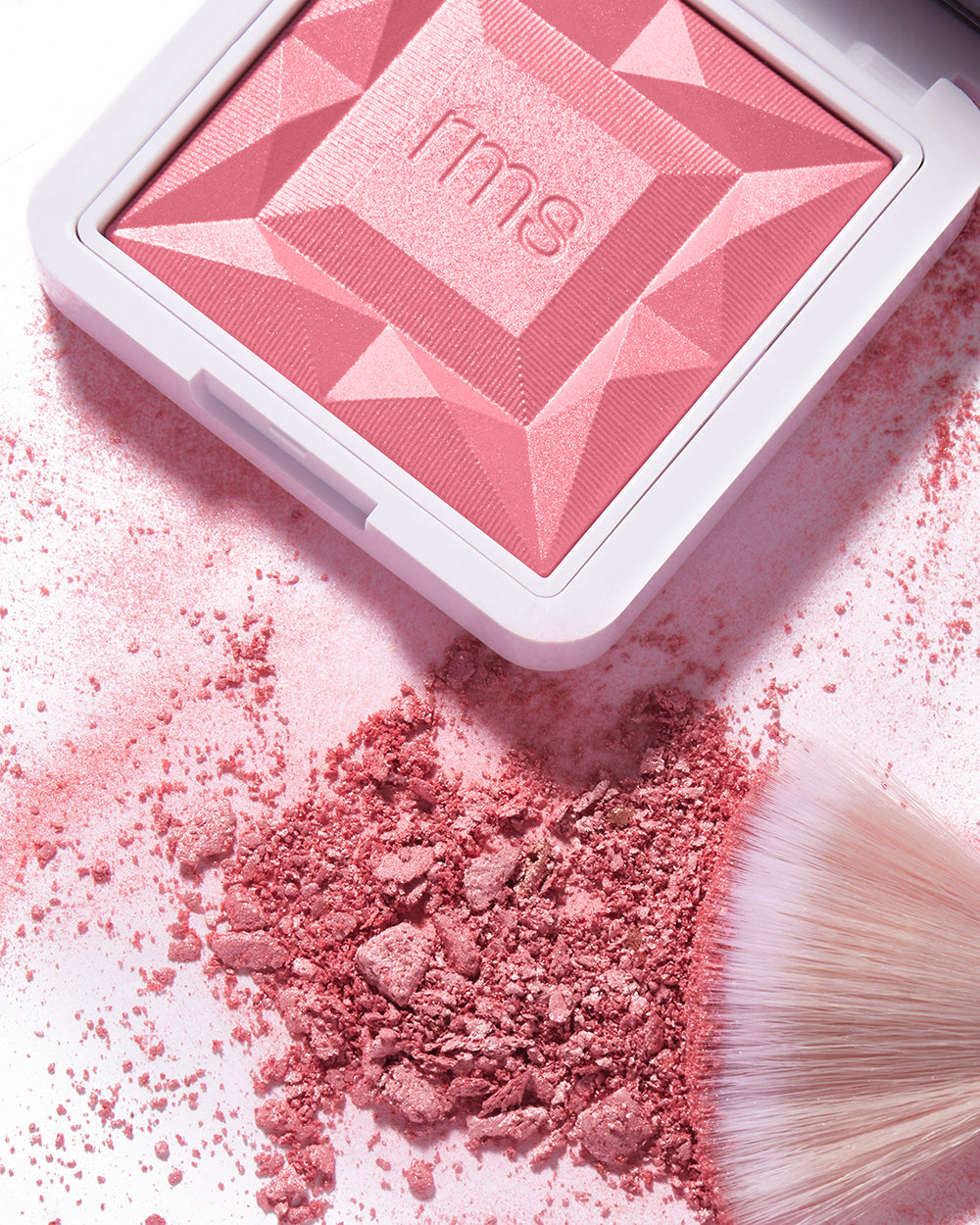 Makeup compact with scattered powder and brush nearby.