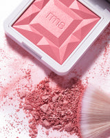 Makeup compact with scattered powder and brush nearby.