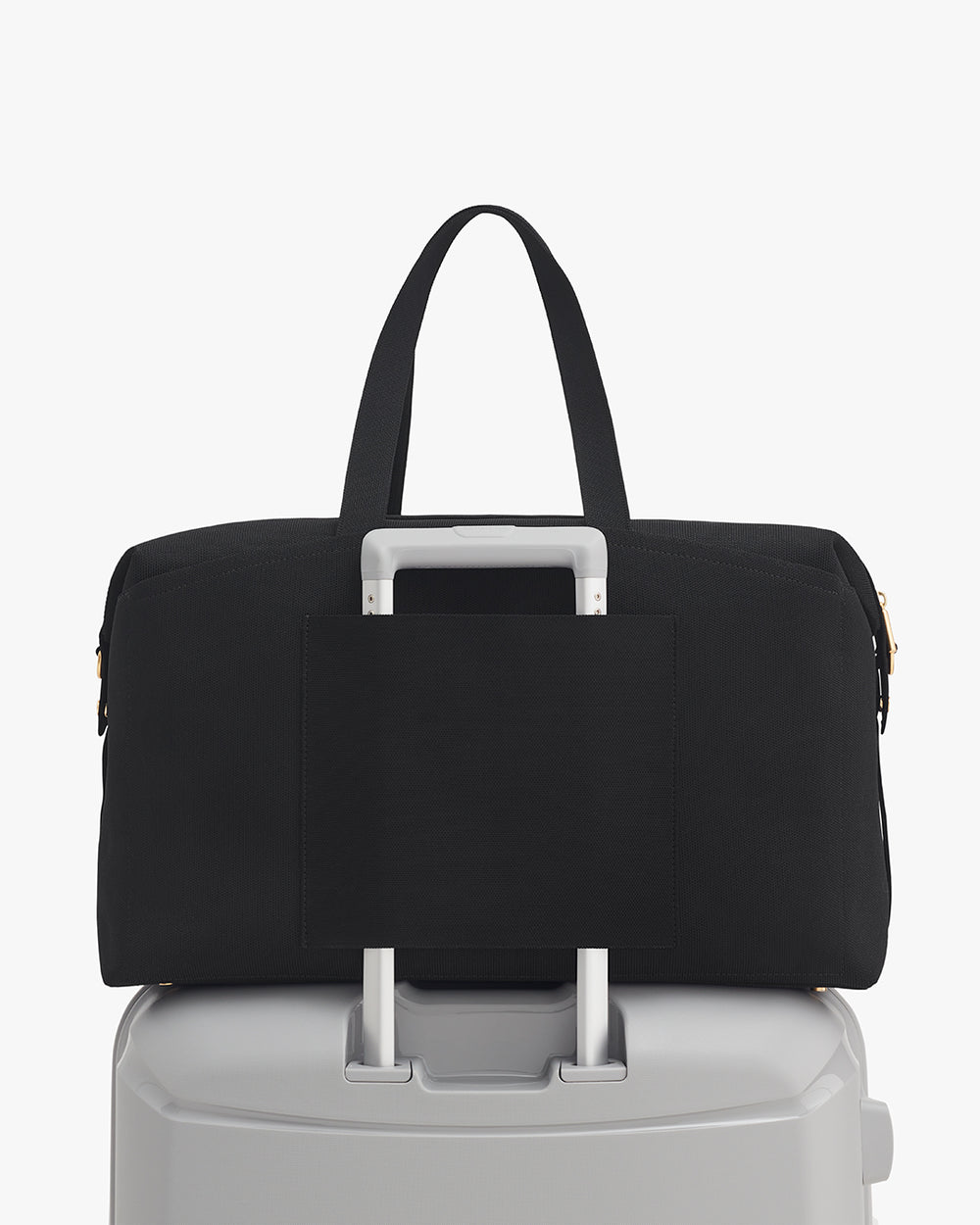 Travel bag on top of a suitcase with handle through strap