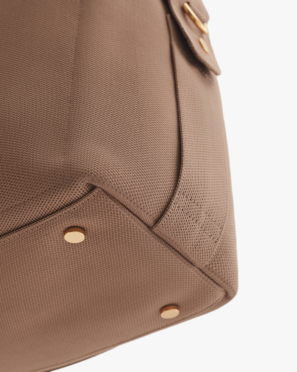 Close-up of a travel bag with metal studs and a pocket flap.