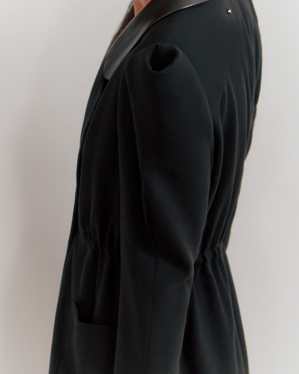 Person wearing a blazer, side view, cropped at shoulders and thighs.