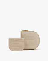 Two small, rounded wallets with textured exteriors and zippers.