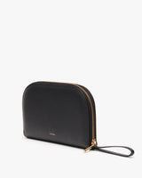 Handbag with zipper and wrist strap standing upright against a plain background
