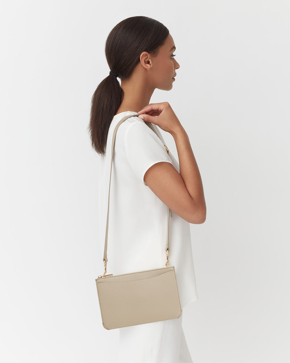 Woman in a top with shoulder-length hair holding a bag, profile view.