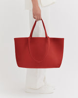 Person holding a large tote bag while standing.