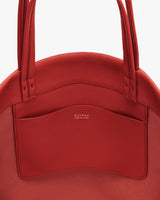 Close-up of a round handbag with a small exterior pocket and two handles.