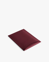 Rectangular leather laptop sleeve with a curved flap closure.