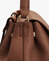 Close-up of a textured leather backpackwith a metal ring attachment.