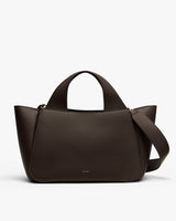Handbag with two handles and a wide strap lying across it