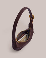 Handbag with open zipper showing items inside, including a white phone and wallet.
