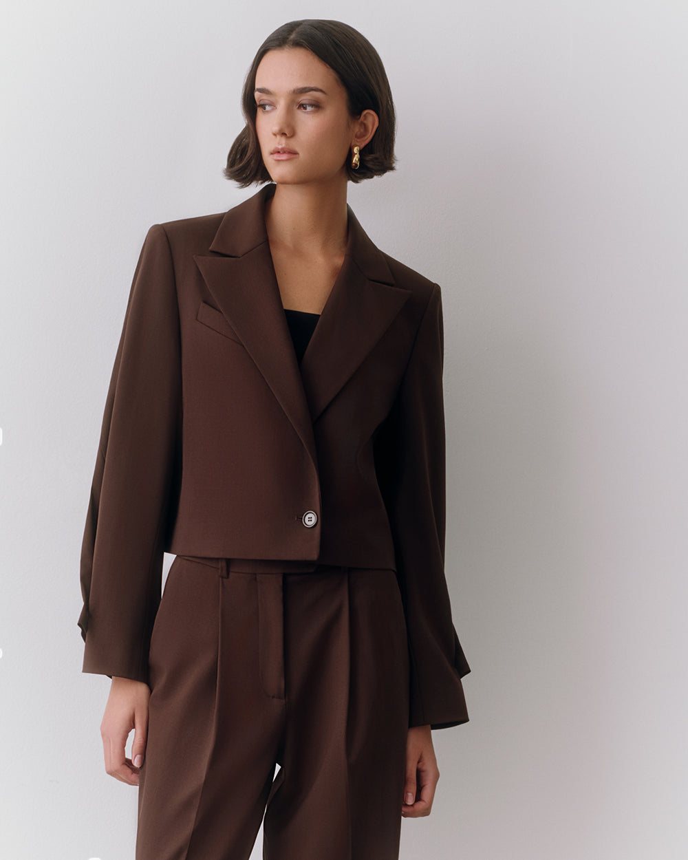 Person wearing a suit jacket and trousers looking to the side.