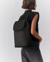 Person carrying a large backpack over one shoulder