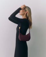 Person with shoulder bag wearing a long-sleeve dress, looking upwards.