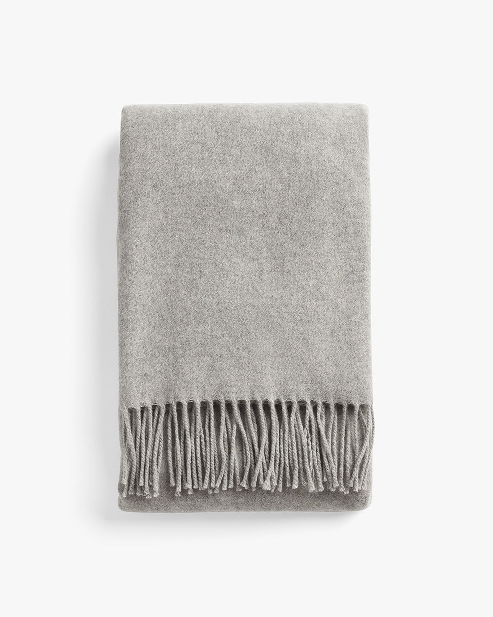 Folded blanket with fringed edges on a plain background.