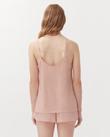 Woman seen from behind wearing a sleeveless top and shorts.