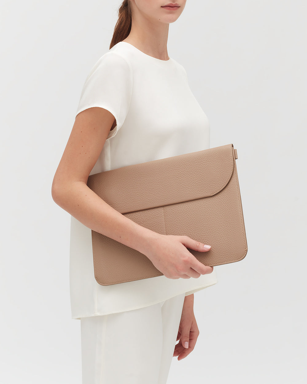 Person holding a large leather laptop sleeve