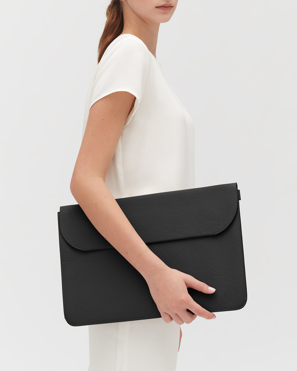 Person holding a large leather laptop sleeve