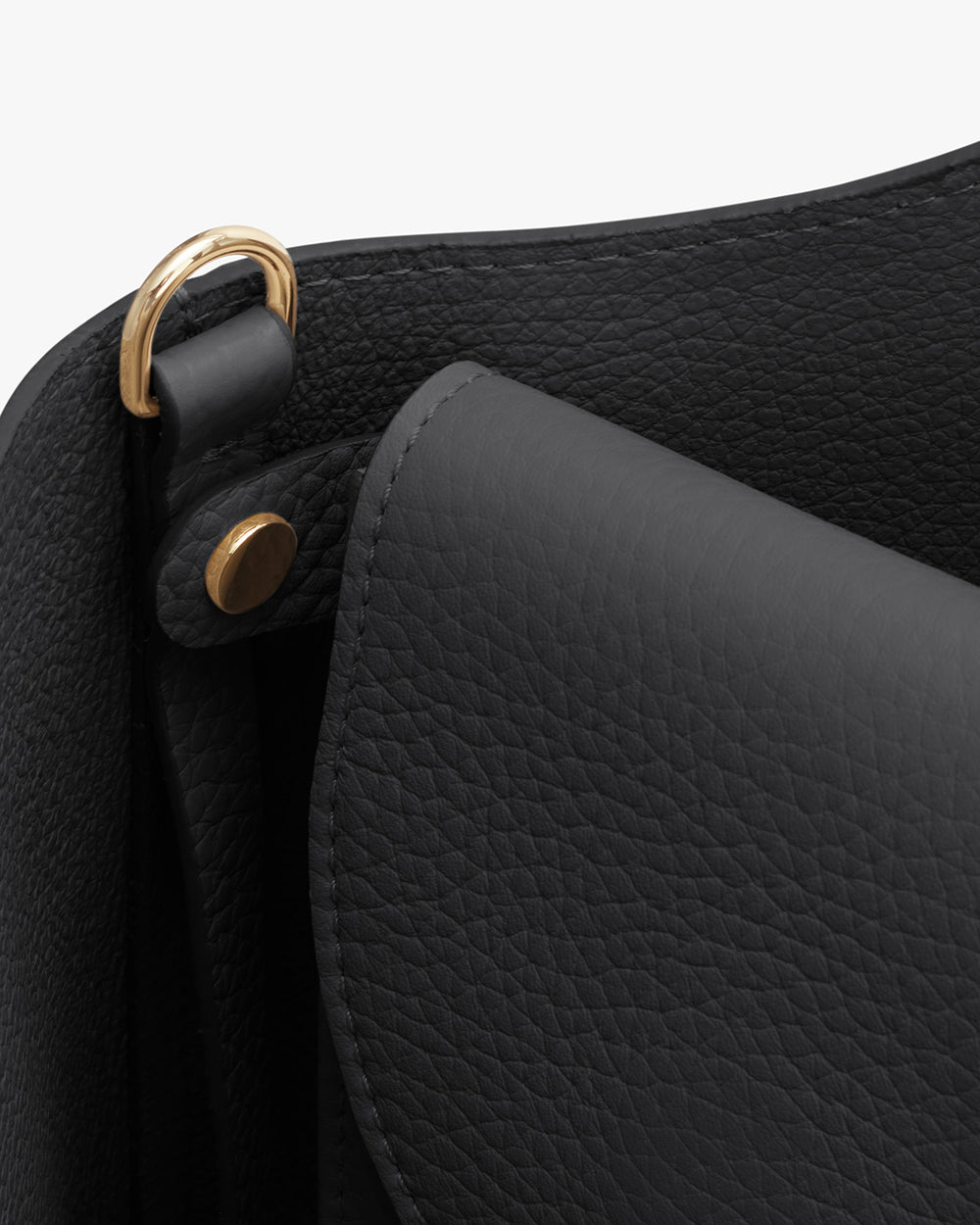 Close-up of a handbag with a flap and metal hardware.