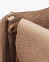 Close-up of a handbag showing partial handle and hardware attachment.