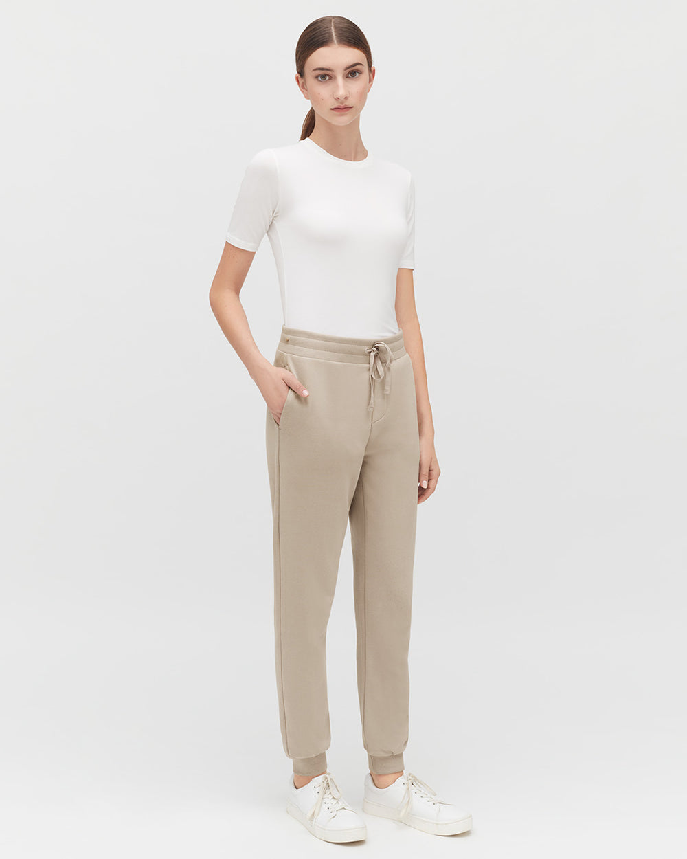 Woman standing in a short-sleeved top and drawstring pants.